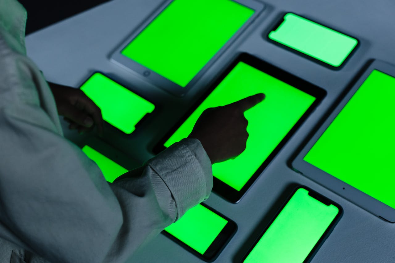 cta-bg Person interacting with multiple green-screen electronic devices indoors.